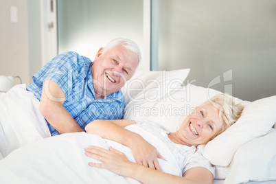 Portrait of happy senior couple relaxing on bed