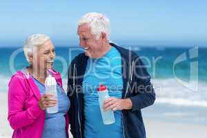 Mature couple holding water bottles together