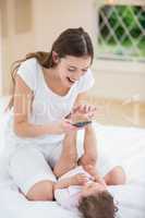 Smiling mother using mobile phone while playing with baby