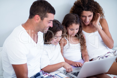 Family using laptop together on bed