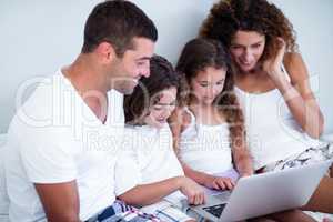 Family using laptop together on bed