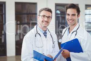 Portrait of smiling male doctors holding clipboards
