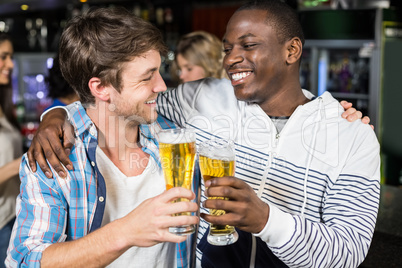 Smiling friends tasting with beer with their friends