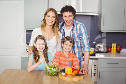 Portrait of smiling family preparing vegetable salad