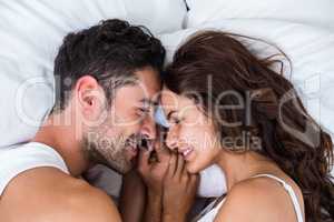 Close-up of smiling couple relaxing on bed