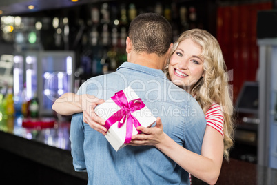 Woman holding present while hugging boyfriend