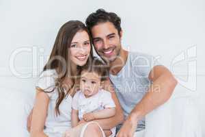Happy couple with baby girl on bed