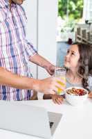 Father giving juice to daughter