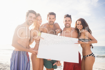 Happy friends in swimwear holding a sign