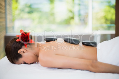 Woman lying with spa stones at her back