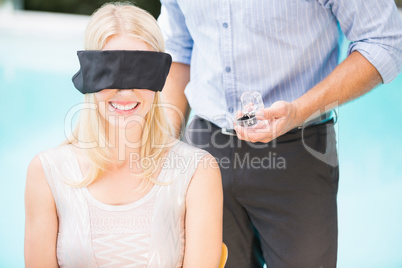 Man holding engagement ring while standing by woman