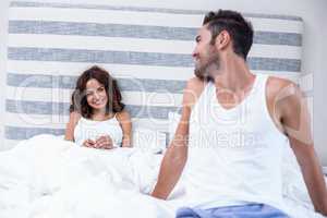 Man looking at wife while sitting on bed