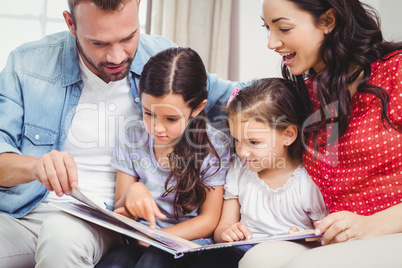 Family looking in picture book while sitting on sofa