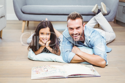 Father and daughter with picture book on floor