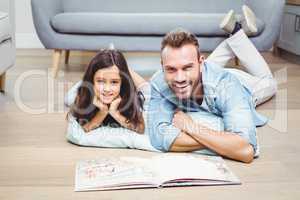 Father and daughter with picture book on floor