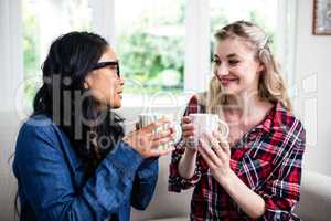 Close-up of female friends drinking coffee at home