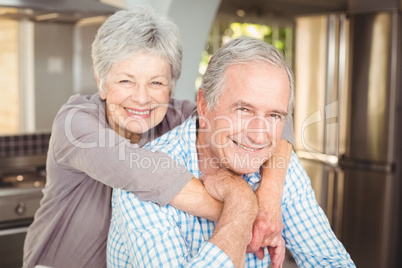 Portrait of cheerful senior couple embracing in kitchen