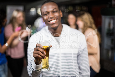 Smiling man showing a beer with his friends