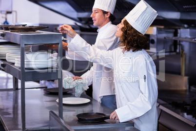 Two chefs working at order station in a kitchen