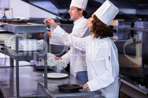 Two chefs working at order station in a kitchen