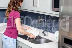 Woman washing plates at kitchen sink