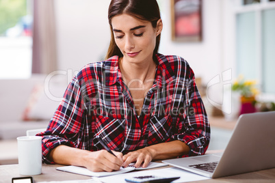 Young woman writing in notepad