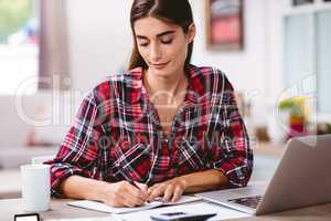 Young woman writing in notepad