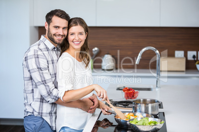 Man embracing woman while preparing food