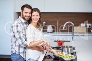 Man embracing woman while preparing food