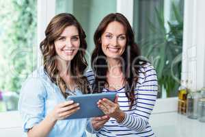 Portrait of happy friends watching video on digital tablet