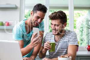 Smiling man showing phone to friend