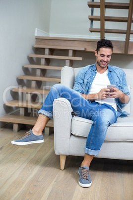 Man using smartphone while sitting on sofa