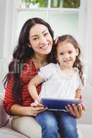 Happy mother with daughter holding digital tablet at home