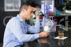 Businessman having a whisky and using laptop