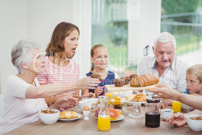 Multi-generation family having muffins during breakfast