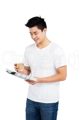 Young man having coffee and reading newspaper