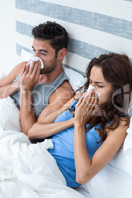 High angle view of young couple covering nose while sneezing on