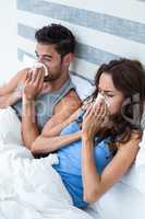 High angle view of young couple covering nose while sneezing on