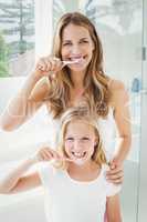 Portrait of smiling mother and daughter brushing teeth