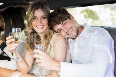 Well dressed couple drinking champagne in a limousine