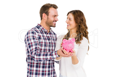 Happy young couple holding piggy bank
