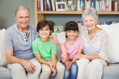 Happy grandchildren with grandparents sitting at home