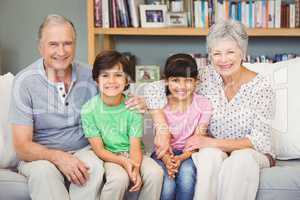 Happy grandchildren with grandparents sitting at home