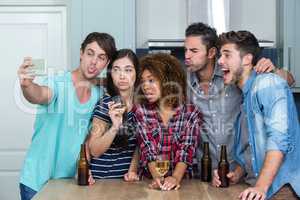 Multi-ethnic young friends making faces while taking selfie