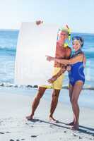 Senior couple with beach equipment holding a white poster