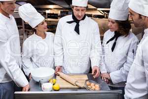 Head chef teaching his team to prepare a dough