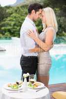 Couple hugging while standing by swimming pool