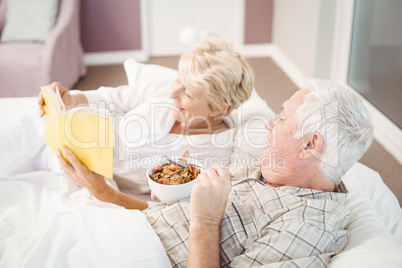 Couple reading book while having breakfast on bed