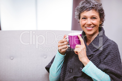 Mature woman with coffee mug sitting on sofa