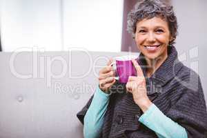 Mature woman with coffee mug sitting on sofa